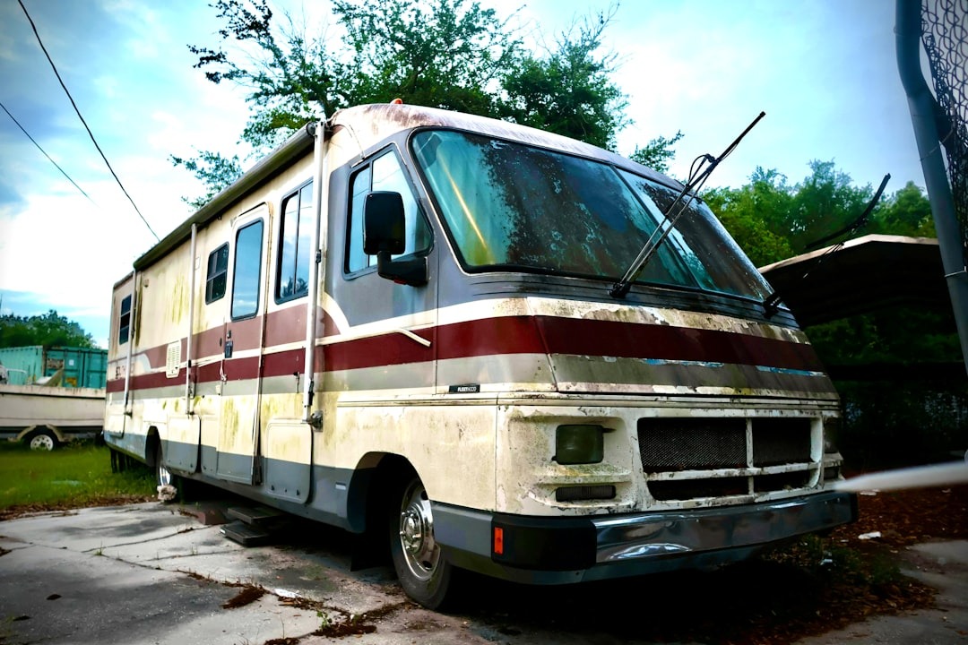 An old, weathered rv parked outdoors on a cloudy day.